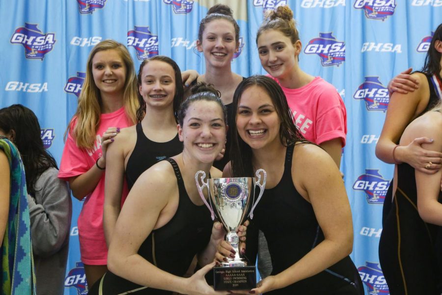 The girls swim team poses with their trophy. From left to right, top row: Hannah Heetderks, Anna Blankenship, Kyla Maloney, Sophie Bell; From left to right, bottom row: Teresa Maloney, Jade Foelske.