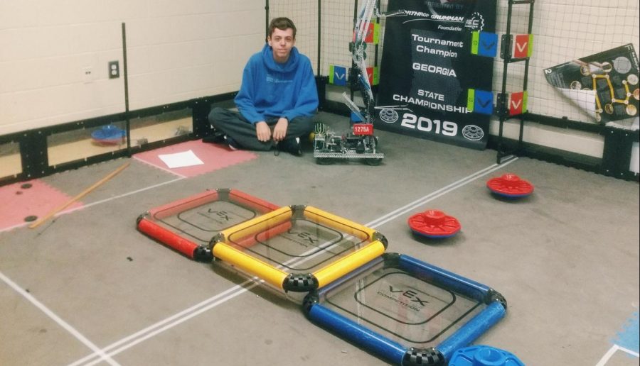 Andrew Council sits next to his robot.