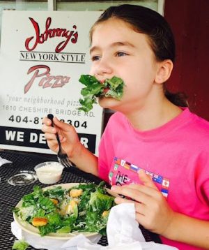 Young staff writer Luiza Douglas chows down on a salad outside the restaurant, Johnnys New York Style Pizza