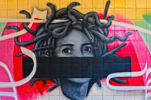 Mural of Medusa, black and white, against a tiled wall of yellow and red