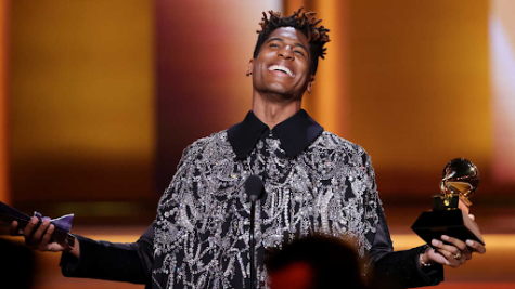 Jon Batiste holding a Grammy and smiling