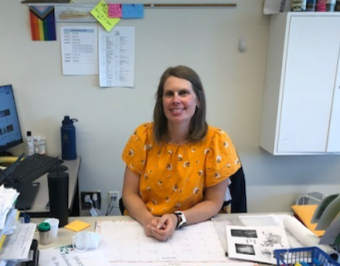 Gross sits at desk, ready to teach students about the environment. 