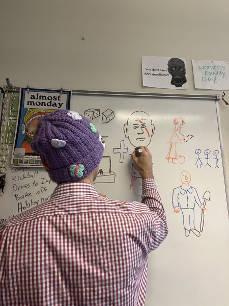 Mr. Avett drawing on a cross on the board. Photo Courtesy of Ellie Owens.