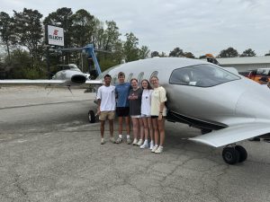 Jonas Maender (‘26), Duke Nichols (‘26), Mallory Williams (‘26), Camille Avery (‘27), and Grace Nichols in front of a plane. Photo courtesy of Mallory Williams (‘26).
