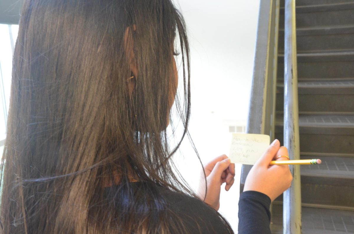 A girl posing pretending to write in the staircase. Photo by Michael Bryant.